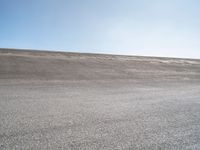 a lone skateboard on the road in a dry field with sky in the background