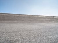 a lone skateboard on the road in a dry field with sky in the background