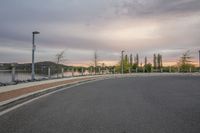 a man is skateboarding down the road next to the river at sunset by himself