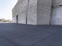 a man riding a skateboard down the side of a road next to a cement building