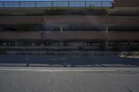 a person riding a skateboard down the middle of a road under a bridge in front of building