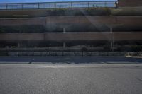 a person riding a skateboard down the middle of a road under a bridge in front of building