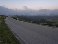 a man riding a skateboard down the middle of a rural road in the evening