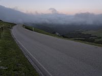 a man riding a skateboard down the middle of a rural road in the evening