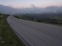 a man riding a skateboard down the middle of a rural road in the evening