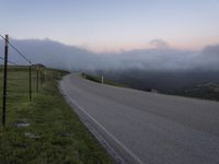 a man riding a skateboard down the middle of a rural road in the evening