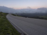 a man riding a skateboard down the middle of a rural road in the evening