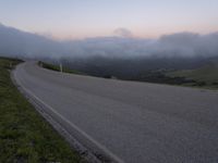 a man riding a skateboard down the middle of a rural road in the evening