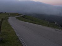 a man riding a skateboard down the middle of a rural road in the evening