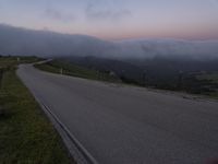 a man riding a skateboard down the middle of a rural road in the evening