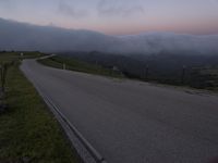 a man riding a skateboard down the middle of a rural road in the evening