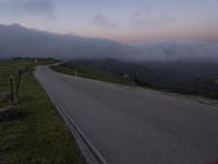 a man riding a skateboard down the middle of a rural road in the evening