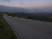 a man riding a skateboard down the middle of a rural road in the evening