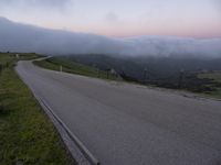 a man riding a skateboard down the middle of a rural road in the evening