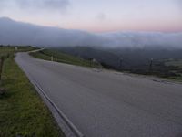 a man riding a skateboard down the middle of a rural road in the evening