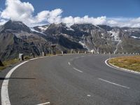 a man is on his skateboard on a paved street near mountains in the swiss alps