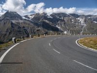 a man is on his skateboard on a paved street near mountains in the swiss alps