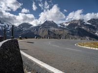 a man is on his skateboard on a paved street near mountains in the swiss alps