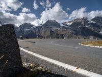 a man is on his skateboard on a paved street near mountains in the swiss alps