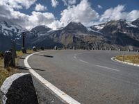 a man is on his skateboard on a paved street near mountains in the swiss alps