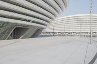 a skateboarder is riding down the street in front of an office building with a curved roof