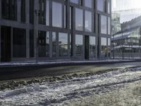 the person is riding a skateboard down the street in the snow near a building