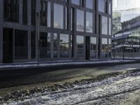 the person is riding a skateboard down the street in the snow near a building