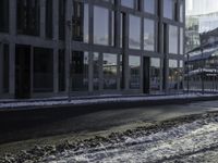 the person is riding a skateboard down the street in the snow near a building