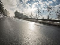 a skateboarder is skating down the snow covered road during a sunny day,