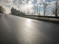 a skateboarder is skating down the snow covered road during a sunny day,