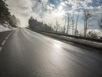 a skateboarder is skating down the snow covered road during a sunny day,