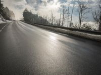 a skateboarder is skating down the snow covered road during a sunny day,