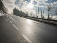 a skateboarder is skating down the snow covered road during a sunny day,