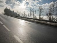 a skateboarder is skating down the snow covered road during a sunny day,