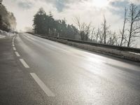 a skateboarder is skating down the snow covered road during a sunny day,