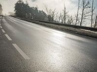 a skateboarder is skating down the snow covered road during a sunny day,