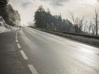 a skateboarder is skating down the snow covered road during a sunny day,