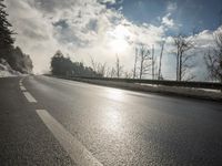a skateboarder is skating down the snow covered road during a sunny day,