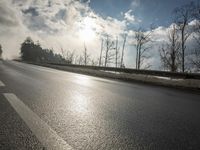 a skateboarder is skating down the snow covered road during a sunny day,