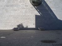 a person riding a skateboard on top of a stone block floor next to a white wall