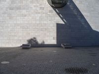 a person riding a skateboard on top of a stone block floor next to a white wall