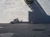 a person riding a skateboard on top of a stone block floor next to a white wall