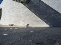 a person riding a skateboard on top of a stone block floor next to a white wall