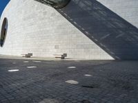 a person riding a skateboard on top of a stone block floor next to a white wall