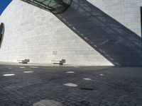 a person riding a skateboard on top of a stone block floor next to a white wall