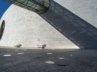 a person riding a skateboard on top of a stone block floor next to a white wall