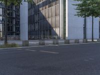 a man rides his skateboard on the street in front of a tall building and trees