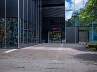 a skateboarder riding on the edge of a skate park in front of large glass walls and windows