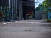 a skateboarder riding on the edge of a skate park in front of large glass walls and windows