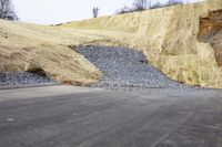 a man is on a skateboard near the road while the wall of a large mountain is eroded off